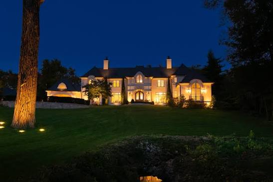 Two-story home illuminated by architectural uplighting at dusk