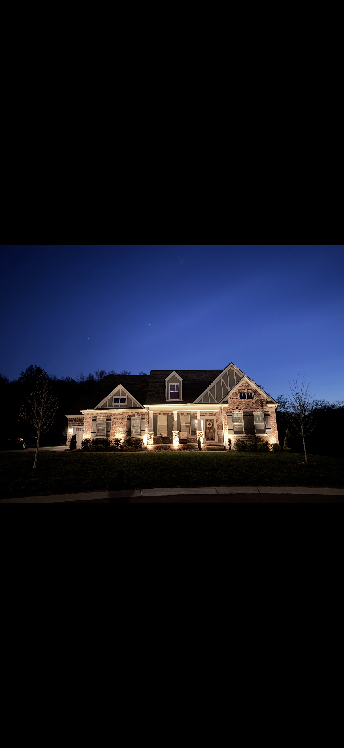 Luxury home glowing with custom landscape lighting at night